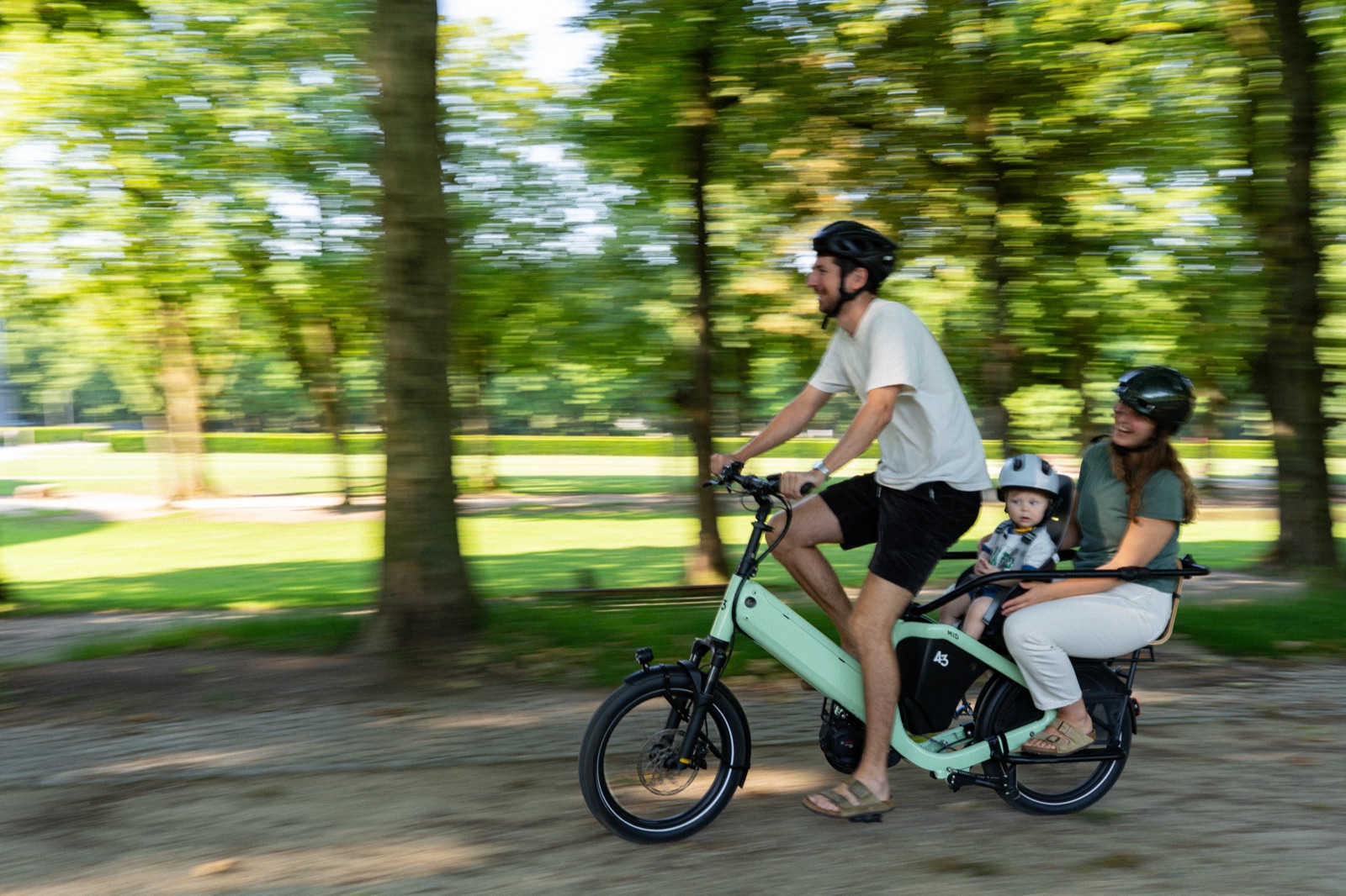 Bike43 Mid in sage green ridden with a baby in a child seat and an adult behind