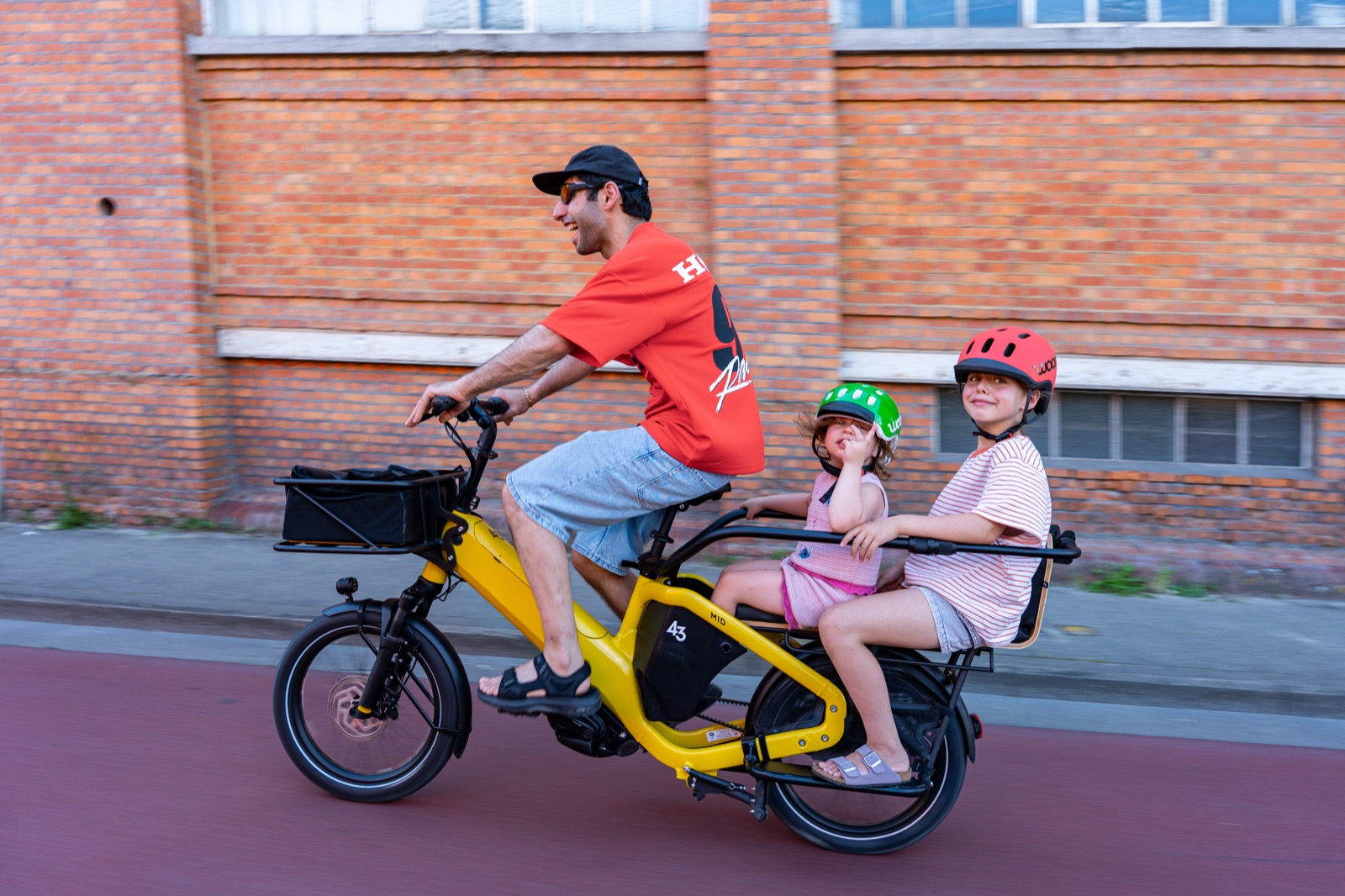 Bike43 Mid in yellow riding along a cycle lane with two children on the back bench