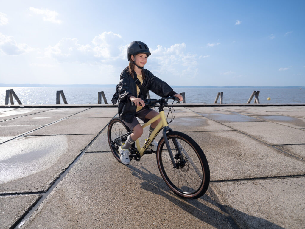 Girl riding a Mellow Yellow woom Explore along a lakeside pier
