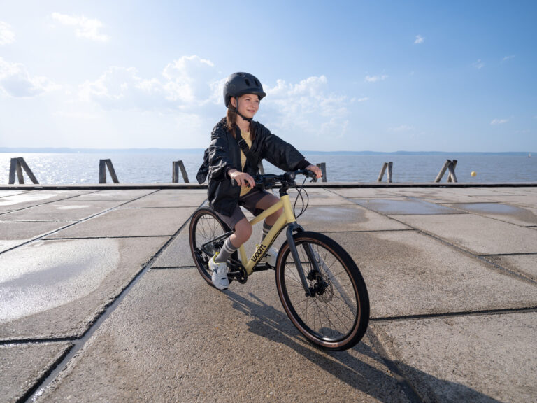 Girl riding a Mellow Yellow woom Explore along a lakeside pier